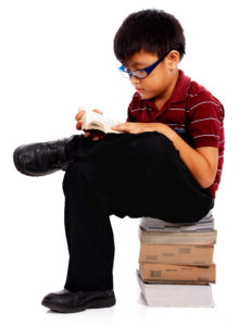 Intelligent Boy Sitting On A Pile Of Books And Reading One